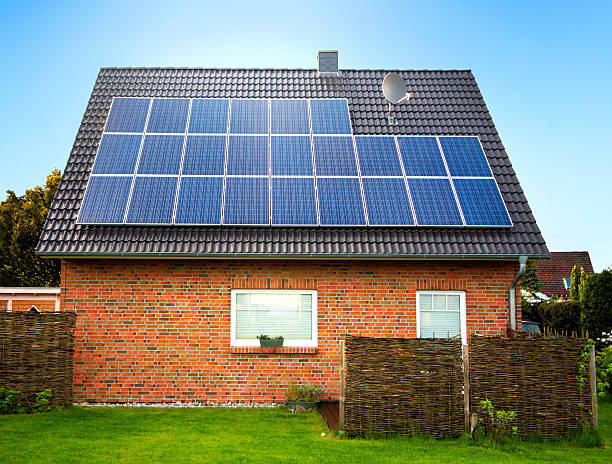 Side view of a large solar panel on a rooftop large solar panel on a rooftop, with dark cloudy background house residential structure roof rooftiles stock pictures, royalty-free photos & images