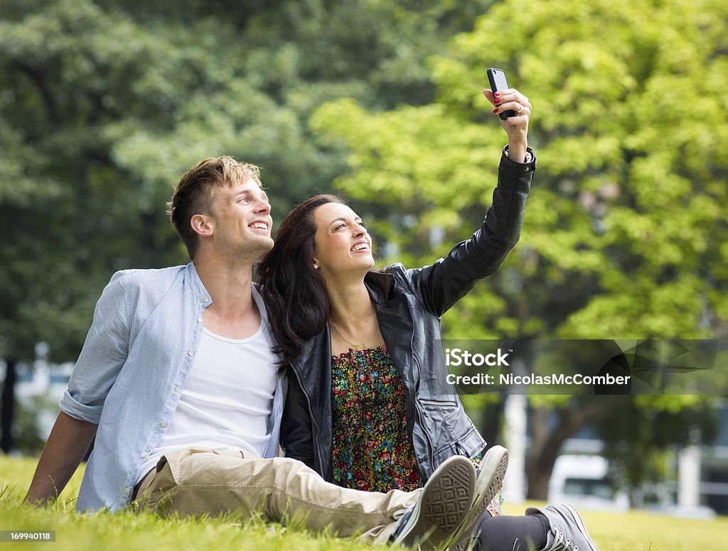 Making Romantic Memories with Smart Phone A young woman takes a picture of herself and her boyfriend in a park using her smart phone. City Stock Photo