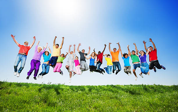 grand groupe de gens de sauter contre le ciel sans nuage. - group of people child teenager multi ethnic group photos et images de collection