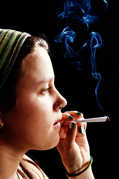 istock Dreamy young woman about to puff on marijuana cigarette 169940631