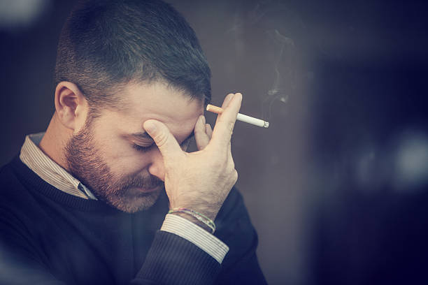 Worried man smoking a cigarette stock photo