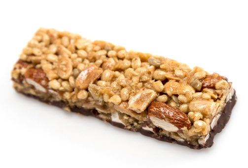 Chocolate, almonds, and peanuts energy bar close up on white background