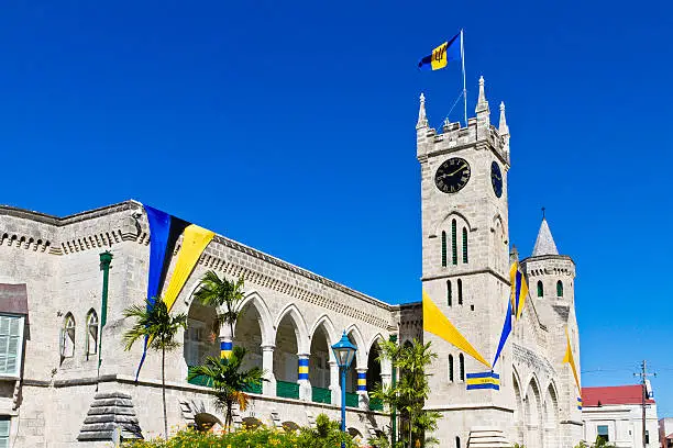 The Parliament Building, completed in 1874, is a masterpiece of Gothic Architecture, built of local coral limestone and strategically placed in the heart of Bridgetown. These buildings house the House of Assembly and the Senate and hold the history of the Barbadian system of Government which is the third oldest political system within the Commonwealth. In this picture, the building facade is adorned with Blue and Gold banners, the colors of Barbados, to celebrate the independence day occurred on 30 November 1966. The celebrations of remembrance continue for the entire month of November.