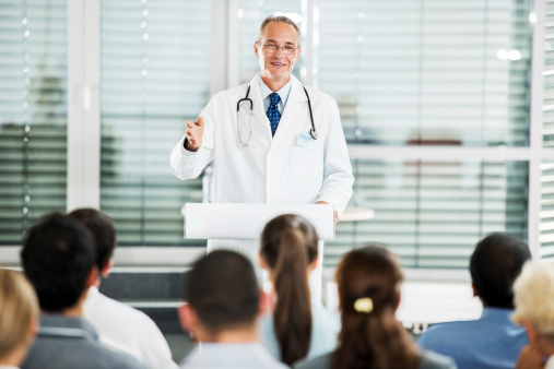 Group of doctors on a seminar. The focus is on mature adult man giving a speech.   