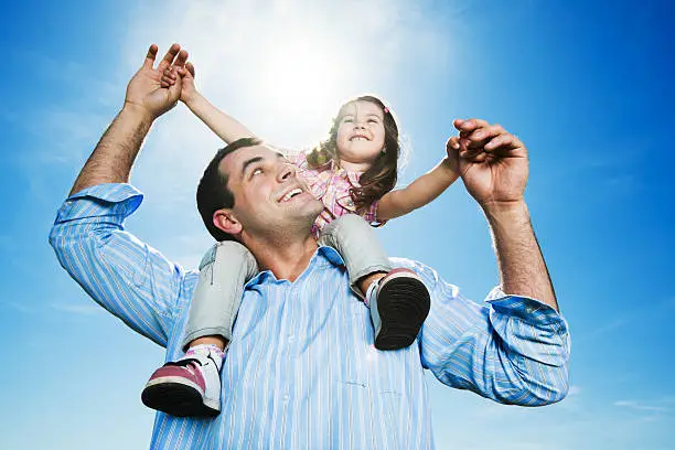 Photo of Father with young daughter on his shoulders