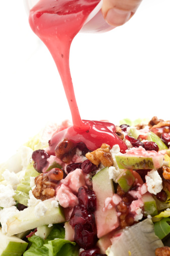 human hand Pouring dressing over a salad