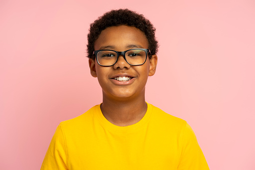 Smiling school boy wearing stylish eyeglasses isolated on pink background. Education concept