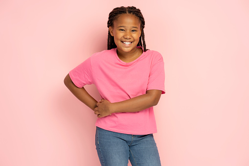 Cute smiling African American girl wearing pink casual t shirt isolated on pink background