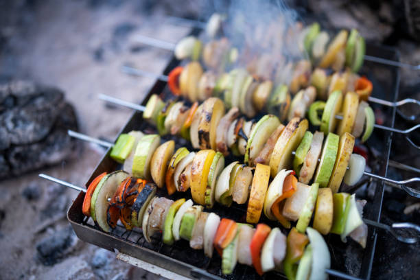 Vegetable skewers preparing on embers on wild camping.Cooking on camping.