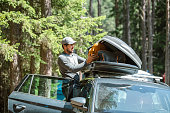 Man filling cargo box container on roof rack for camping vacation.