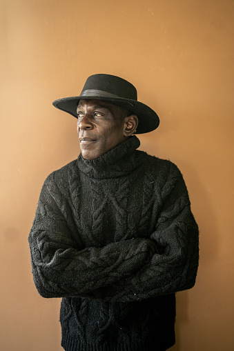 Portrait of a black mature man with crossed hands and a black hat