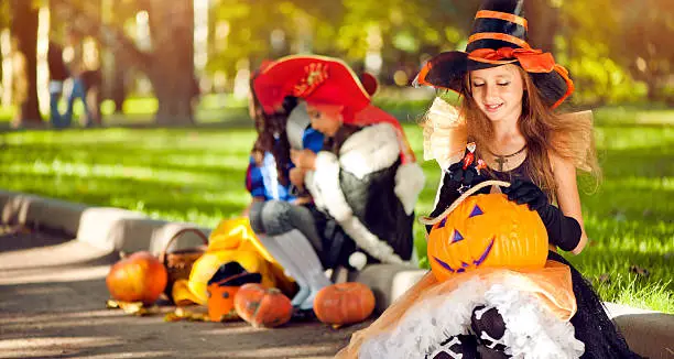 Three little girls dressed up for Halloween posing outdoors