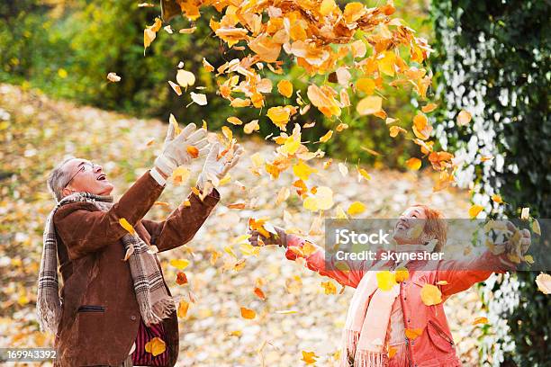 Beautiful Mature Couple In The Heap Of Leaves Stock Photo - Download Image Now - Autumn, Leaf, Mature Couple