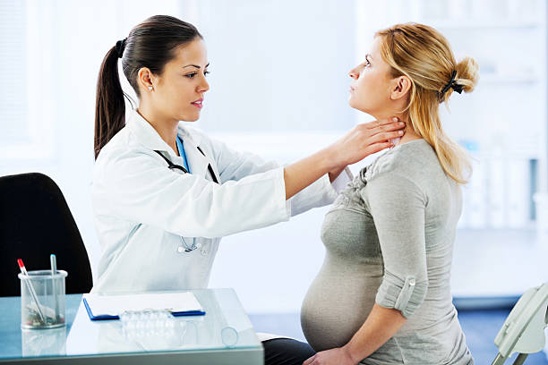 femmina medico esaminando il suo paziente in stato di gravidanza. - goiter foto e immagini stock