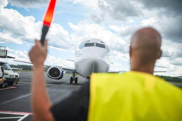 istock Mixed Race Airport Worker Marshalling An Aircraft 1699436620
