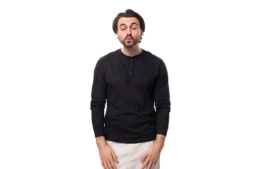 portrait of a young handsome brunette man with a haircut and a beard dressed in a black jacket isolated on a white background with copy space.