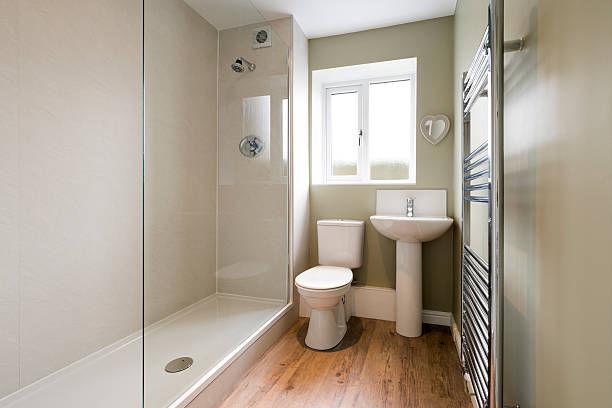 Modern compact bathroom Light streaming in through the window of a compact, minimalist modern bathroom, completely renovated, with waterproof boarding, shower tray, a large glass splash screen, heated towel rail, and walls painted in a subtle French Grey colour. A halogen ceiling light contributes to the overall lighting in this image. screen partition stock pictures, royalty-free photos & images