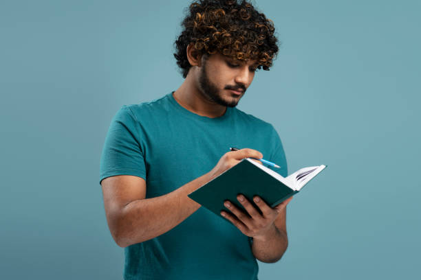 istock Confident young man taking notes on his notepad, isolated over blue color background 1699441383
