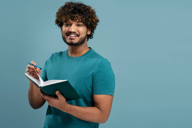 istock Handsome confident young man taking notes on his notepad, isolated over blue color background 1699441390