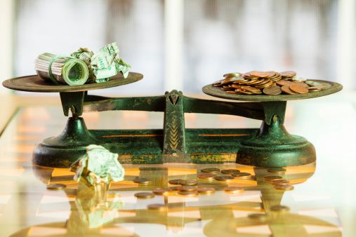 coins and paper currency on the antique scales