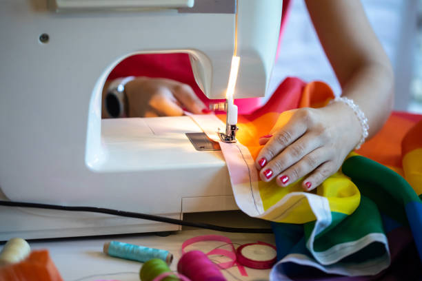 Hands guiding stripy flag material on a sewing machine stock photo