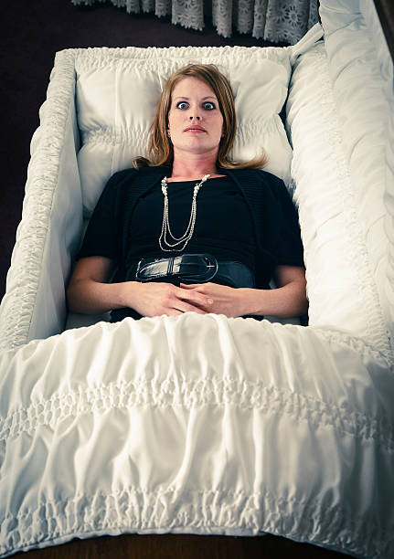 Dead or Alive A woman laying in a casket with her eyes wide open. coffin photos stock pictures, royalty-free photos & images