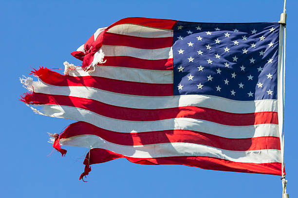 Tattered American Flag, Still Flying Free and Proud Tattered American Flag, Still Flying Free and Proud.  This image is symbolic of the American spirit, even when tired and rough around the edges, America goes forward. run down stock pictures, royalty-free photos & images