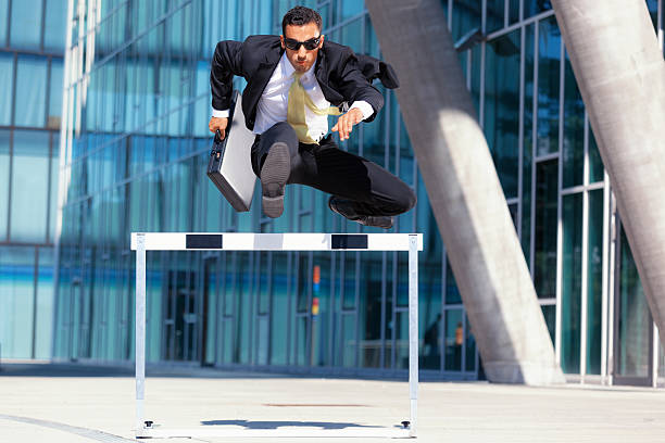 business man on the run young business man with briefcase and sunshades running over hurdle hurdling track event stock pictures, royalty-free photos & images