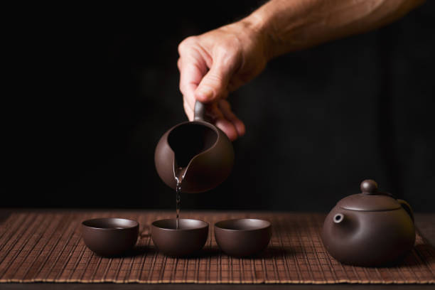 istock Person pouring tea from a teapot into teacups 1699463083