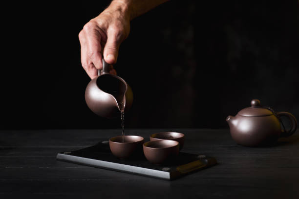 istock Person pouring tea from a teapot into teacups 1699463588