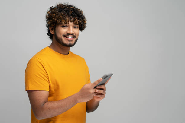 istock Smiling Indian man holding smartphone using mobile app shopping online, copy space. Mobile banking 1699464115