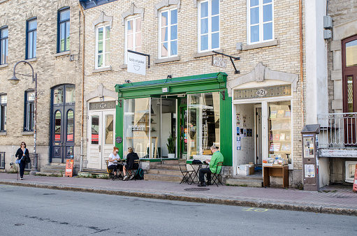 Facade of poke bowl restaurant with people eating while sitting on tables on the sidewalk during summer day in Quebec city