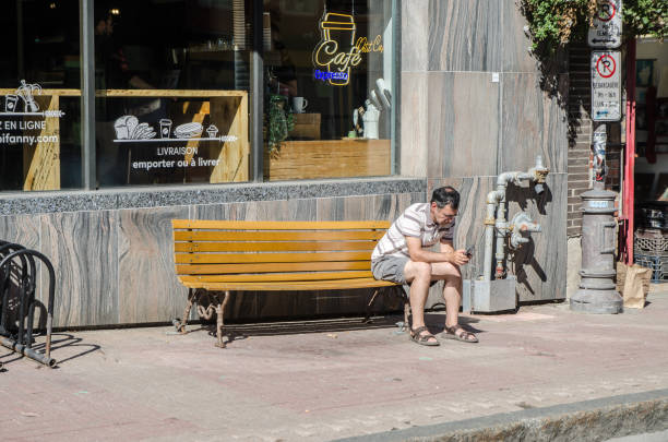 Lonely man sitting on a wooden bench outdoors in a park in autumn day