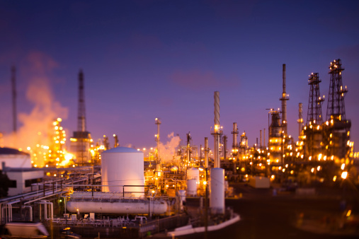 Tilt-shifted photograph of a large oil refinery or chemical plant complex at dusk