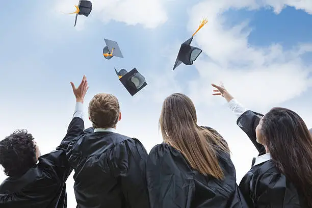 Photo of Excited group of college graduates throwing their hats in celebration