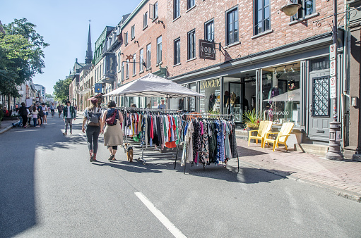 Clothing store doing a street sale during summer day in Quebec city with pedestrians