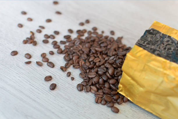 istock Coffee beans poured from a vacuum bag onto the table. Close-up 1699489835