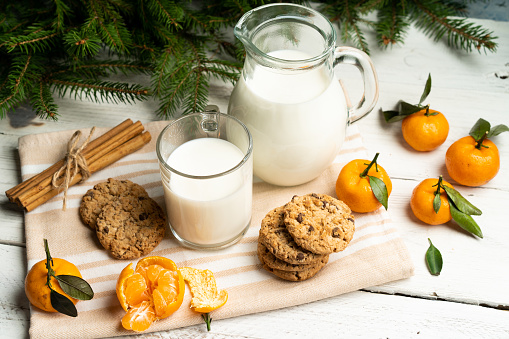 milk and cookies on the table against the backdrop of the Christmas tree, a treat for Santa Claus, Christmas traditions.
