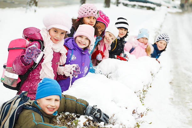 Beautiful children are enjoying in the snow. They are looking at the camera.   
