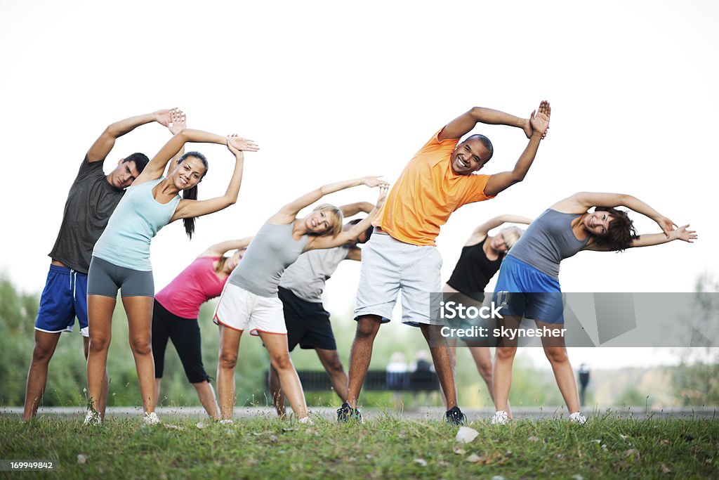 Group of people doing stretching exercises. Large group of people exercising together in the nature.    Aerobics Stock Photo