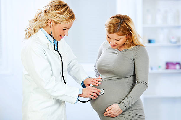 istock Gynecologist checking pregnant woman's belly with stethoscope. 169950432