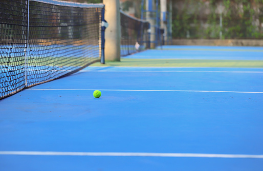 A tennis ball on a blue tennis court