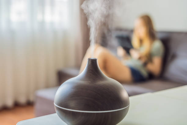 istock Aromatherapy Concept. Wooden Electric Ultrasonic Essential Oil Aroma Diffuser and Humidifier. Ultrasonic aroma diffuser for home. Woman resting at home 1699536091