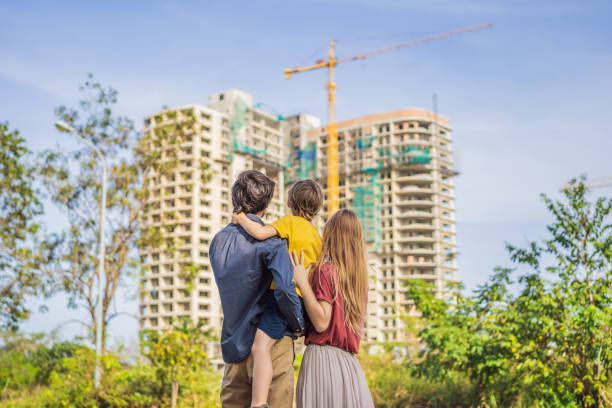 Family mother, father and son looking at their new house under construction, planning future and dreaming. Young family dreaming about a new home. Real estate concept stock photo