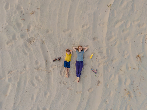 Mom and son are lying on the sand at sunset. View from the drone. Paradise, travel, vacation concept.