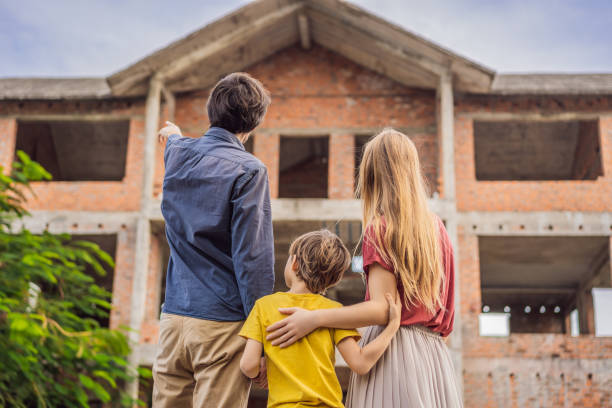 family mother, father and son looking at their new house under construction, planning future and dreaming. young family dreaming about a new home. real estate concept - stockyards industrial park imagens e fotografias de stock