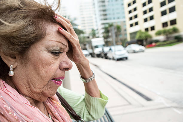 uma aparência envelhecida mulher em pé sobre uma cidade rua. - senior women defeat headache frustration - fotografias e filmes do acervo