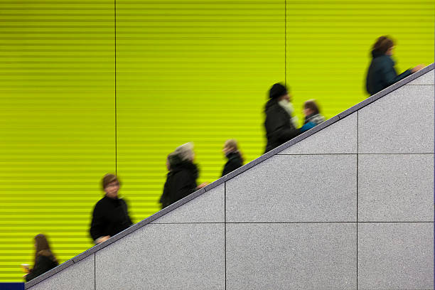 Civilians riding an escalator with a green screen background motion blurred commuters at modern underground platform - grey marble in front - copy space - camera canon 5D mark II - unsharped RAW - adobe colorspace mall walker stock pictures, royalty-free photos & images