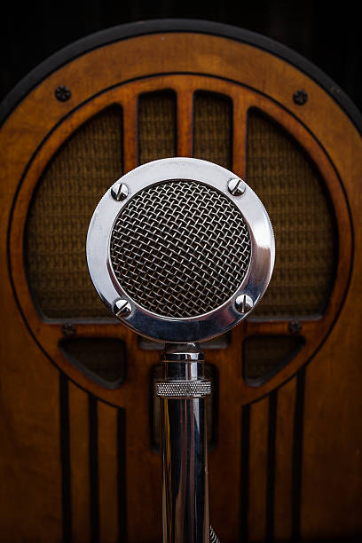 Antique Radio and Announcer's Microphone Still life shot of a shiny antique metal announcer's microphone and a wooden vintage radio from the same era (circa 1930). Shallow focus. radio retro revival old old fashioned stock pictures, royalty-free photos & images