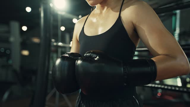 Close-up shot of female boxers hands in boxing gloves. Young woman preparing for intense kickboxing training.